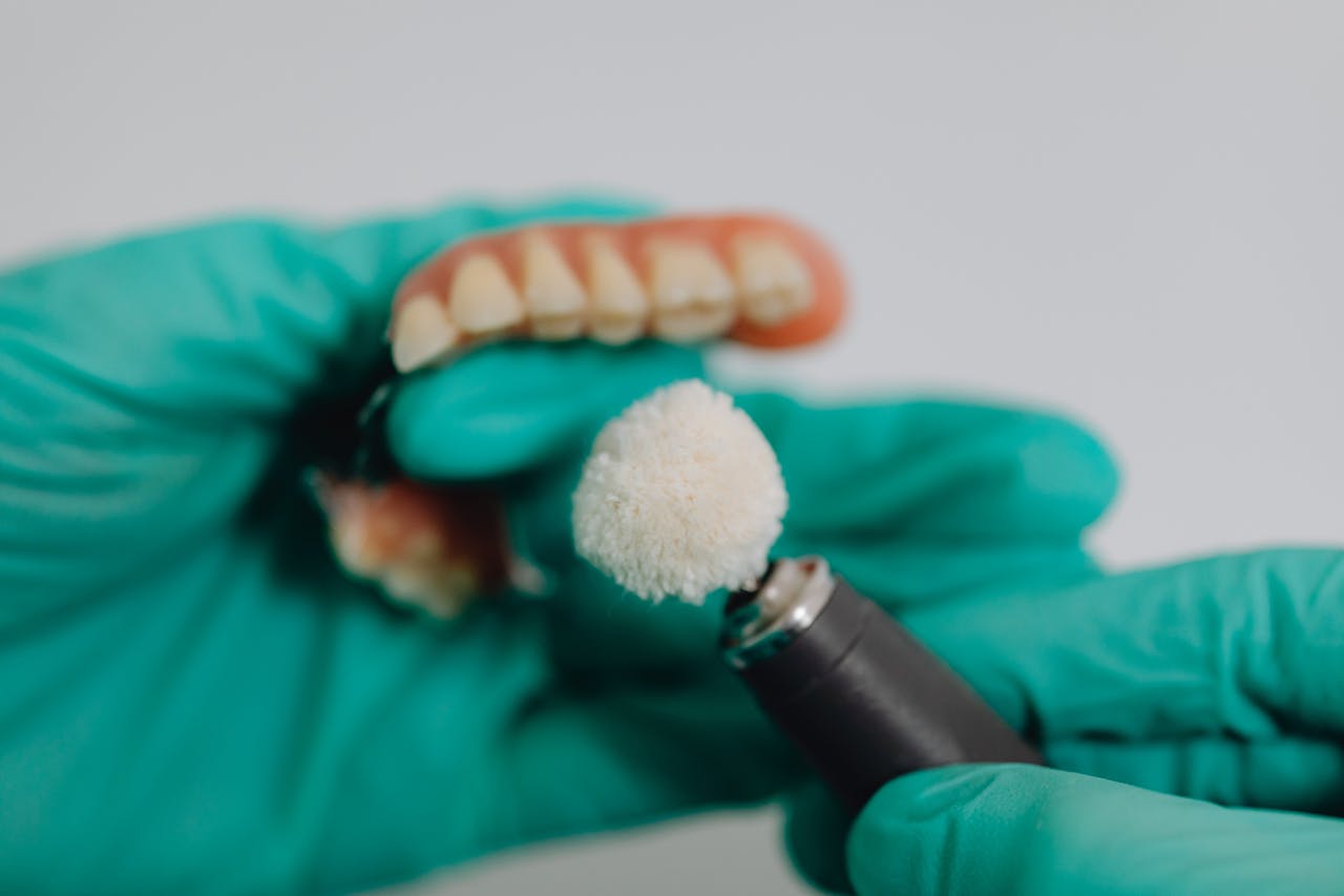 Detailed image of dentures being polished by a dental professional wearing gloves. Ideal for dental care topics.
